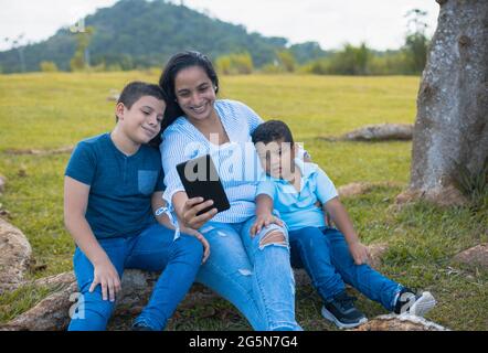 Latino Mutter und Söhne sitzen beim Selfie Stockfoto