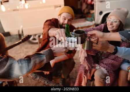 Eine Gruppe von Freunden toasten mit alkoholischen Getränken und feiern ihren Urlaub bei einem Picknick im Wald Stockfoto