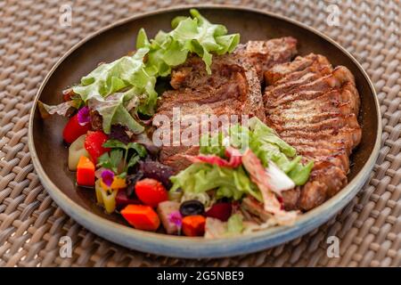 Gegrilltes, gehacktes T-Bone Steak, serviert mit Salat und Gemüse im Beachfront Cafe Stockfoto