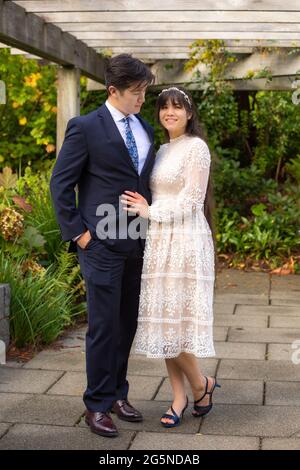 Frisch verheiratete Biracial Braut und Bräutigam lächeln im Freien unter Holz Pergola Stockfoto