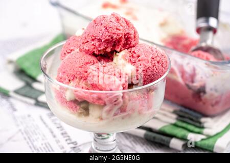 Erdbeerjoghurt in Glasschüssel, Eiskugeln, Behälter mit hausgemachten Eisgläsern Stockfoto
