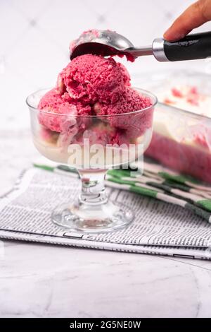 Erdbeerjoghurt in Glasschüssel, Eiskugeln, Behälter mit hausgemachten Eisgläsern Stockfoto