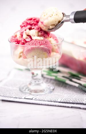 Erdbeerjoghurt in Glasschüssel, Eiskugeln, Behälter mit hausgemachten Eisgläsern Stockfoto