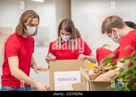 Freiwillige tragen Schutzmasken und packen Spendenboxen Stockfoto