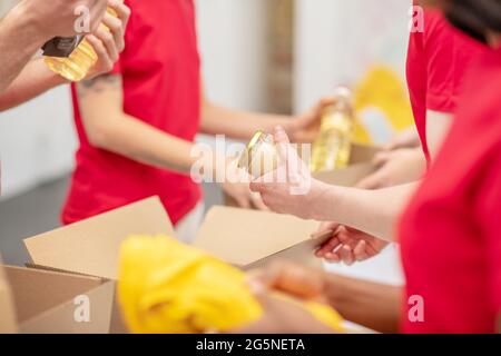 Junge Leute packen ihre Hände mit Lebensmitteln und Kleidung Stockfoto