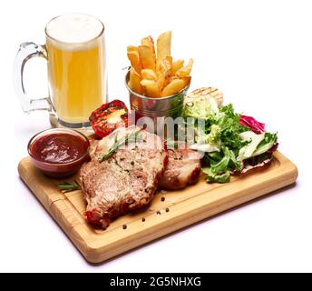 Gegrillte Rindersteaks, Kartoffeln, Sauce und Salat auf Holzschneidebrett Stockfoto