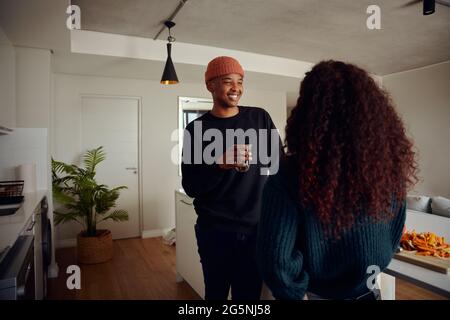 Gemischtes Rennpaar trinkt zusammen Kaffee. Junger, glücklicher afroamerikanischer Mann, der seine Partnerin anlächelt. Hochwertige Fotos Stockfoto