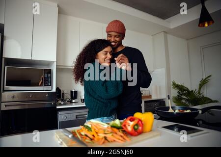 Junges, glückliches gemischtes Rennpaar, das sich in der Küche die Hände hält. Gemischtes Rennpaar tanzt zusammen und hat Spaß. Hochwertige Fotos Stockfoto