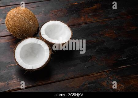 Kokosnusshälften, Kokosnussstücke auf altem dunklen Holztischhintergrund, mit Platz für Text Stockfoto