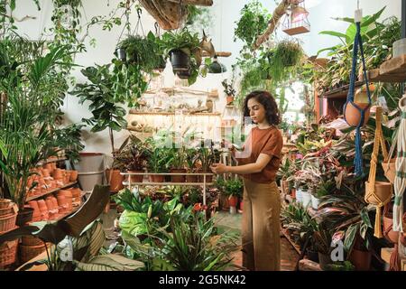 Junge Frau, die sich um die Pflanzen kümmert, während sie im Garten arbeitet Stockfoto
