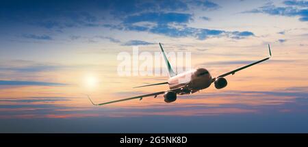 Passagiere Verkehrsflugzeug fliegen über Wolken in Sonnenuntergang Licht. Konzept für schnelle Reisen, Urlaub und Business. Stockfoto