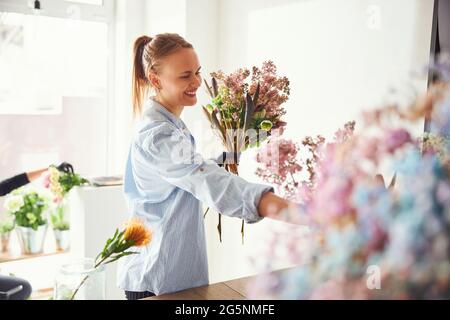 Fröhlicher Blumendesigner, der einen Frühlingsstrauß kreiert Stockfoto