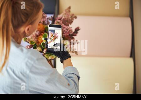 Blumendesignerin fotografiert exotische Blumen in ihrer Hand Stockfoto