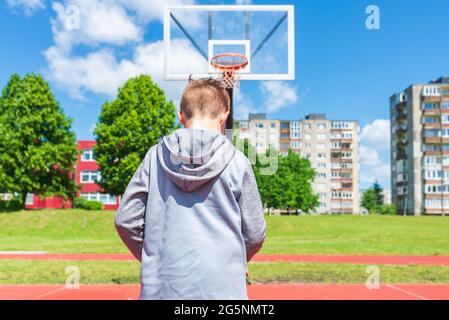 Junge Vorbereitung für Basketball-Schießen auf Playground.Boy führt Schuss bei Basketball-Spiel auf dem Spielplatz während sonnigen Sommertag. Stockfoto