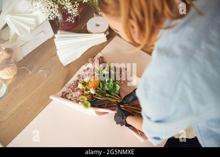 Professionelle weibliche Floristin, die einen Blumenstrauß einwickelt Stockfoto