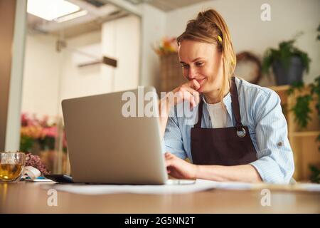 Eine fröhliche, fokussierte Frau liest eine E-Mail auf ihrem Laptop Stockfoto
