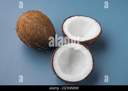 Kokosnusshälften, Set aus Kokosnussteilen, auf blauem texturiertem Sommerhintergrund Stockfoto