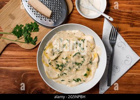 Ravioli mit Pilzen, Parmigiano, Petersilie und frischem Basilikum. Holztisch-Anordnung. Nahaufnahme. Draufsicht Stockfoto