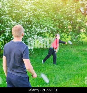 Ein Mann mit einem Jungen, der auf dem Rasen im Park Badminton spielt Stockfoto