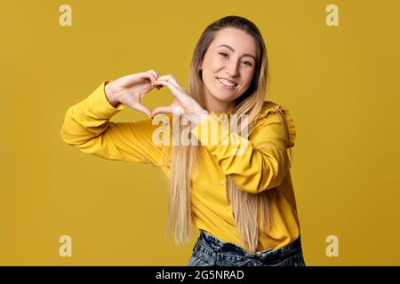 Frau mit Liebesgesten auf gelbem Hintergrund. Stockfoto