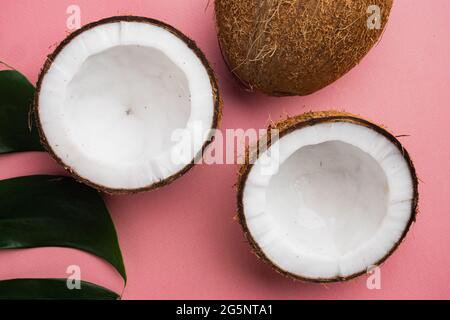 Kokosnusshälften, Set aus Kokosnussteilen, auf rosa strukturiertem Sommerhintergrund Stockfoto