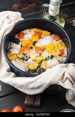 Eine Pfanne fabelhafter Fisch, mit Basmati-Reis und Kirschtomaten, auf einem alten Holztisch Stockfoto