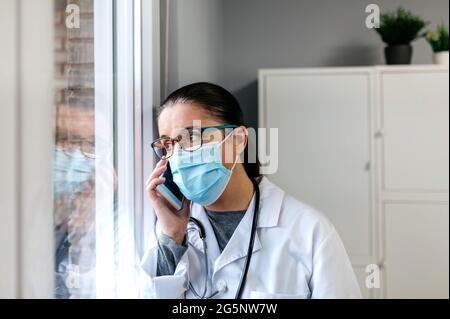 Ärztin im Gespräch auf dem Handy Blick auf die Angezeigt Stockfoto