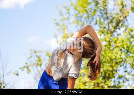 Defocus caucasian preteen Mädchen tun körperliche Bewegung im Park, Wald, im Freien, draußen. Meditation, Konzentration. Gesunder Lebensstil. Seitenbiegung exer Stockfoto