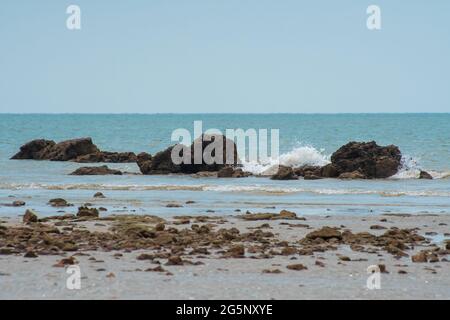 Seascape mit felsigem Strand und Wellen, die auf die Felsen oder die Meeressteine krachen, die ein Spray bilden. Endau, Malaysia Stockfoto