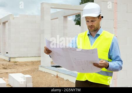 Architekt arbeitet mit Bauplänen auf der Baustelle. Projektsteuerung und -Überwachung Stockfoto