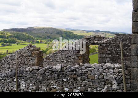 Altes Bauernhaus mit Trockenmauern mit sanften Hügeln und grünen Feldern in der Ferne in Yorkshire Dales Stockfoto