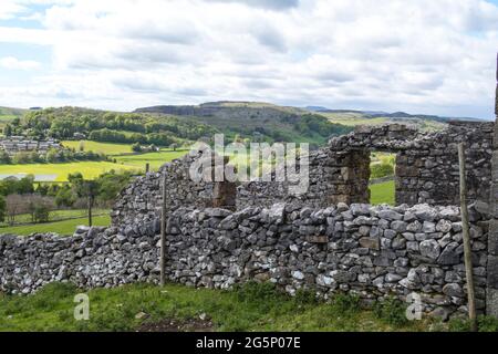 Altes Bauernhaus mit Trockenmauern mit sanften Hügeln und grünen Feldern in der Ferne in Yorkshire Dales Stockfoto