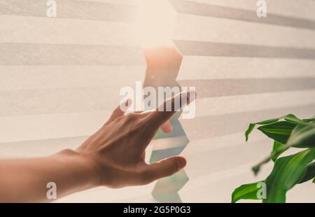 Junge weibliche Hand greift vorsichtig zwischen einen plisee-Bereich, um die Sonnenstrahlen zu sehen Stockfoto
