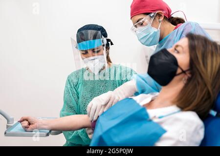 Medizinische Arbeiter tragen Gesichtsmasken, die Blut von weiblichen Patienten zeichnen. Stockfoto