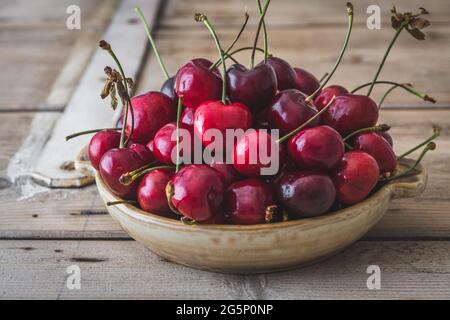 Rustikale Schüssel mit frischen roten Kirschen auf einem alten rustikalen Holztisch Stockfoto