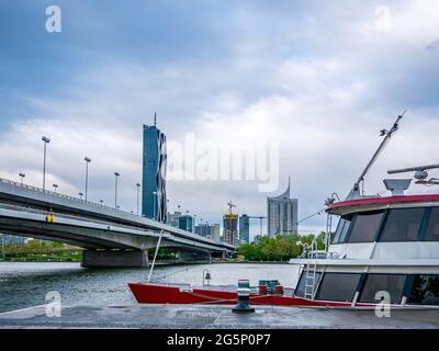 WIEN, ÖSTERREICH - 05. MAI 2021: Donau mit Schiffen und dem DC-Turm im Hintergrund in Wien, Wien, Österreich an einem bewölkten Tag. Stockfoto