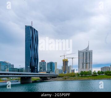 WIEN, ÖSTERREICH - 05. MAI 2021: Donau mit Schiffen und dem DC-Turm im Hintergrund in Wien, Wien, Österreich an einem bewölkten Tag. Stockfoto