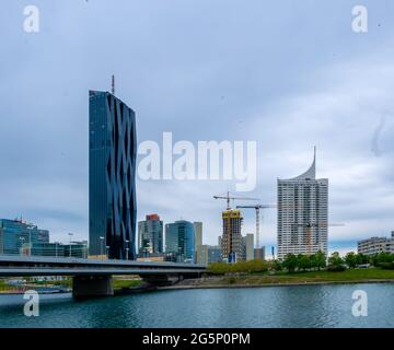 WIEN, ÖSTERREICH - 05. MAI 2021: Donau mit Schiffen und dem DC-Turm im Hintergrund in Wien, Wien, Österreich an einem bewölkten Tag. Stockfoto