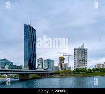 WIEN, ÖSTERREICH - 05. MAI 2021: Donau mit Schiffen und dem DC-Turm im Hintergrund in Wien, Wien, Österreich an einem bewölkten Tag. Stockfoto