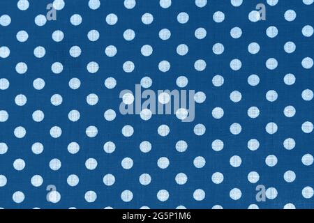 Polka-Punkt auf klassischer blauer Canvas-Baumwollstruktur. Blauer Stoff mit bedruckten weißen Kreisen. Heller Baumwollhintergrund Stockfoto