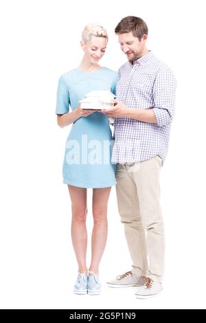 In voller Länge Studio Porträt von schönen Mann und schöne Frau tragen lässige Outfits halten Haus Modell in den Händen, weißer Hintergrund Stockfoto