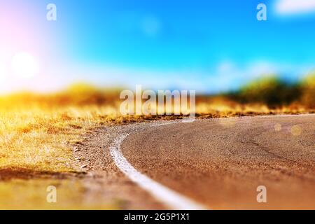 Leere asphaltierte Landstraße und blauer Himmel Naturlandschaft bei Sonnenuntergang. Abstrakte Detail Kurve Landstraße. Stockfoto