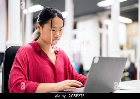Junge asiatische Büroangestellte mit Laptop und arbeiten im Büro. Co-Working-Konzept. Stockfoto