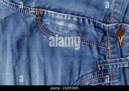 Blaue Jeans Stoff Hintergrundstruktur. Distressed Denim mit Nähten, Vordertasche und Knopf Stockfoto