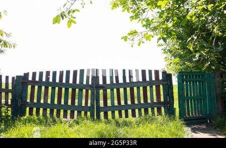 Panoramasicht auf das alte Holztor mit Bäumen im Garten und einer grünen Wiese an einem sonnigen Sommertag Stockfoto