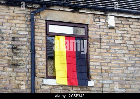 Am Tag, an dem sich England und Deutschland beim Euro2020-Turnier treffen, fliegt eine deutsche Flagge aus einem Fenster eines Hauses in New Mills, Derbyshire. Stockfoto