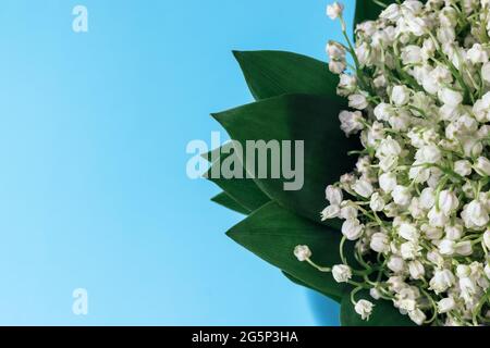 Bouquet von weißen Lilien des Tales in grünen Blättern auf einem weichen blauen Hintergrund mit Kopierraum. Selektiver Fokus. Nahaufnahme. Stockfoto