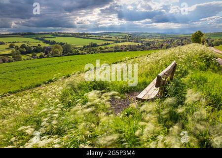 Holzbank mit Blick auf das Dorf East Garston und das Lambourn Valley im Frühjahr, East Garston, West-berkshire, England, Vereinigtes Königreich, Europa Stockfoto