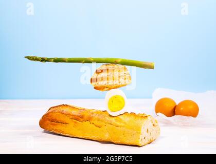 Frisches Brot, Spargel und Ei. Zum Frühstück gibt es Inridients. Gleichgewichtsschwimmende Lebensmittel. Balance Levitation Food. Gesunde Vitamin-Ernährung Stockfoto