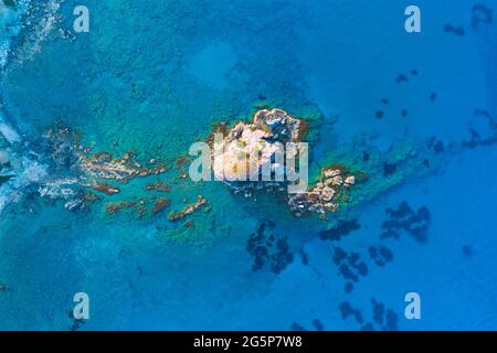 Insel und flaches Wasser im Blauen Ozean. Scharfe Klippe aus Stein. Felsiges Riff mit türkisfarbenem Wasser, Meereswellen auf wunderschönen Strand Luftaufnahme Drohne geschossen Stockfoto